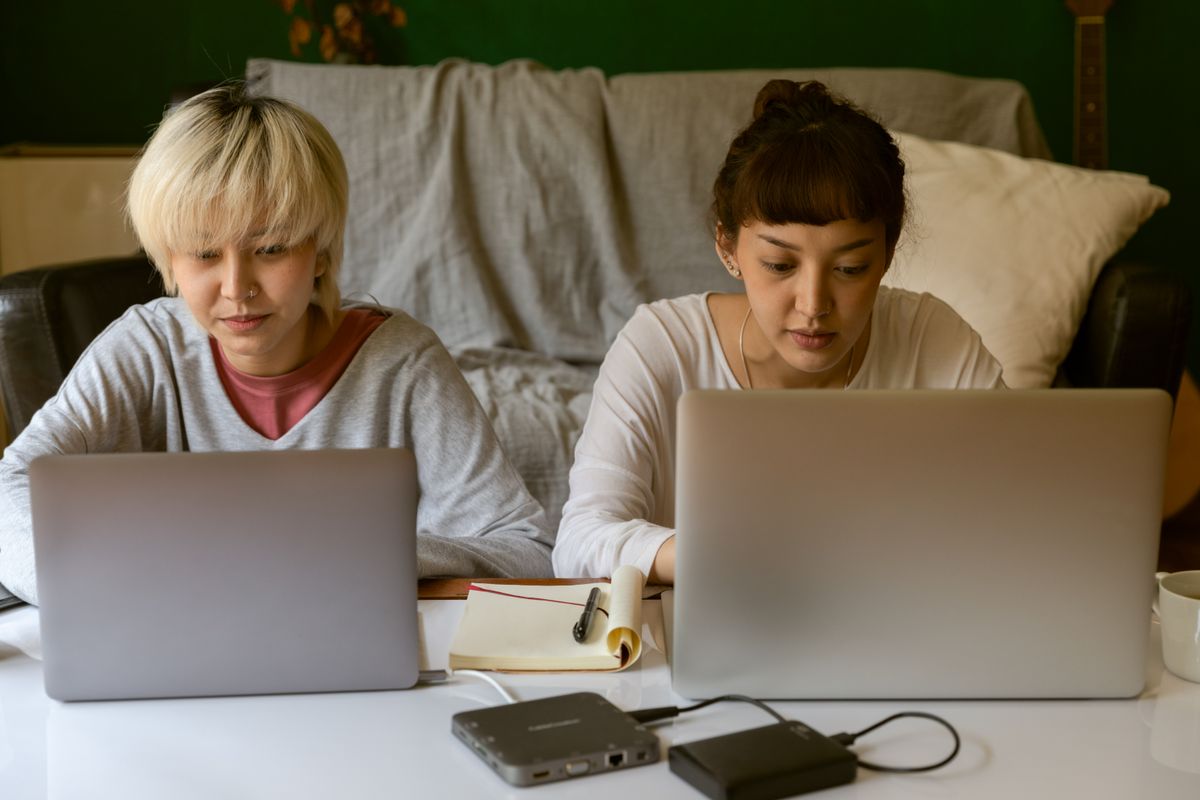 Two people working online on laptops at home